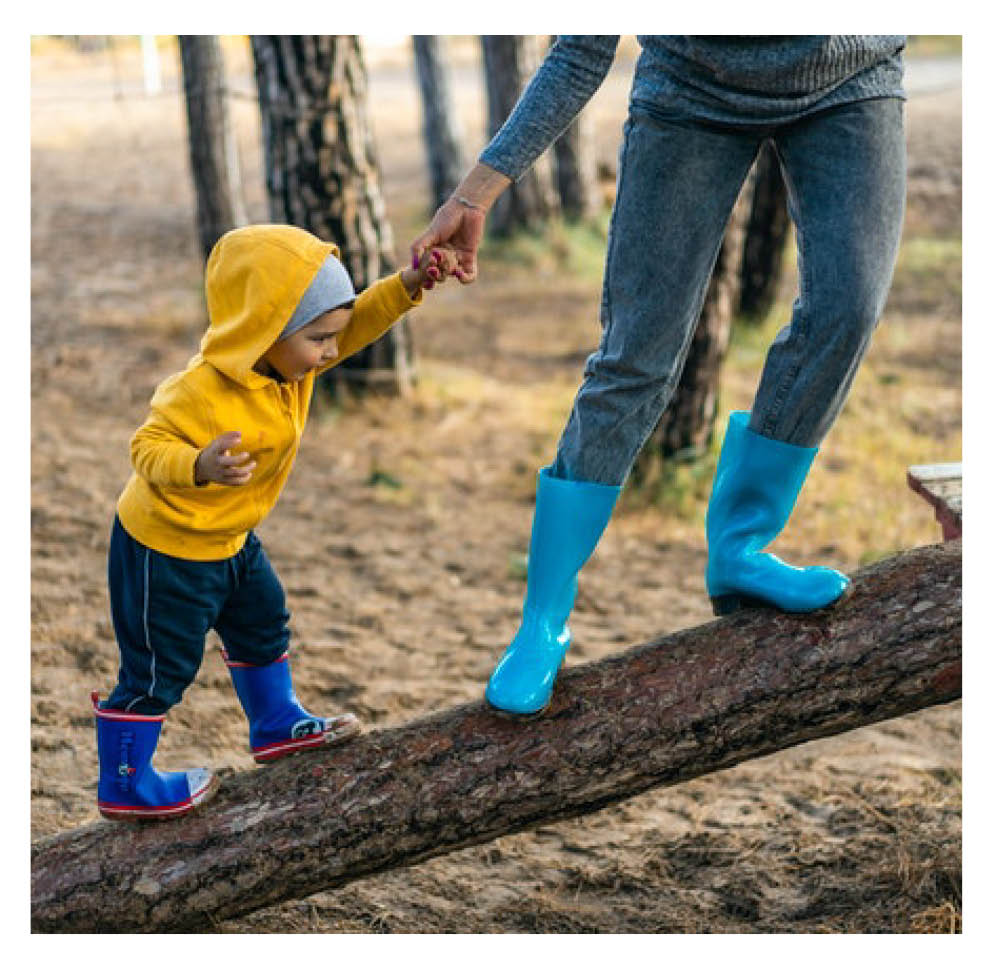 Parent holding child's hand and guiding them up a wooden beam.