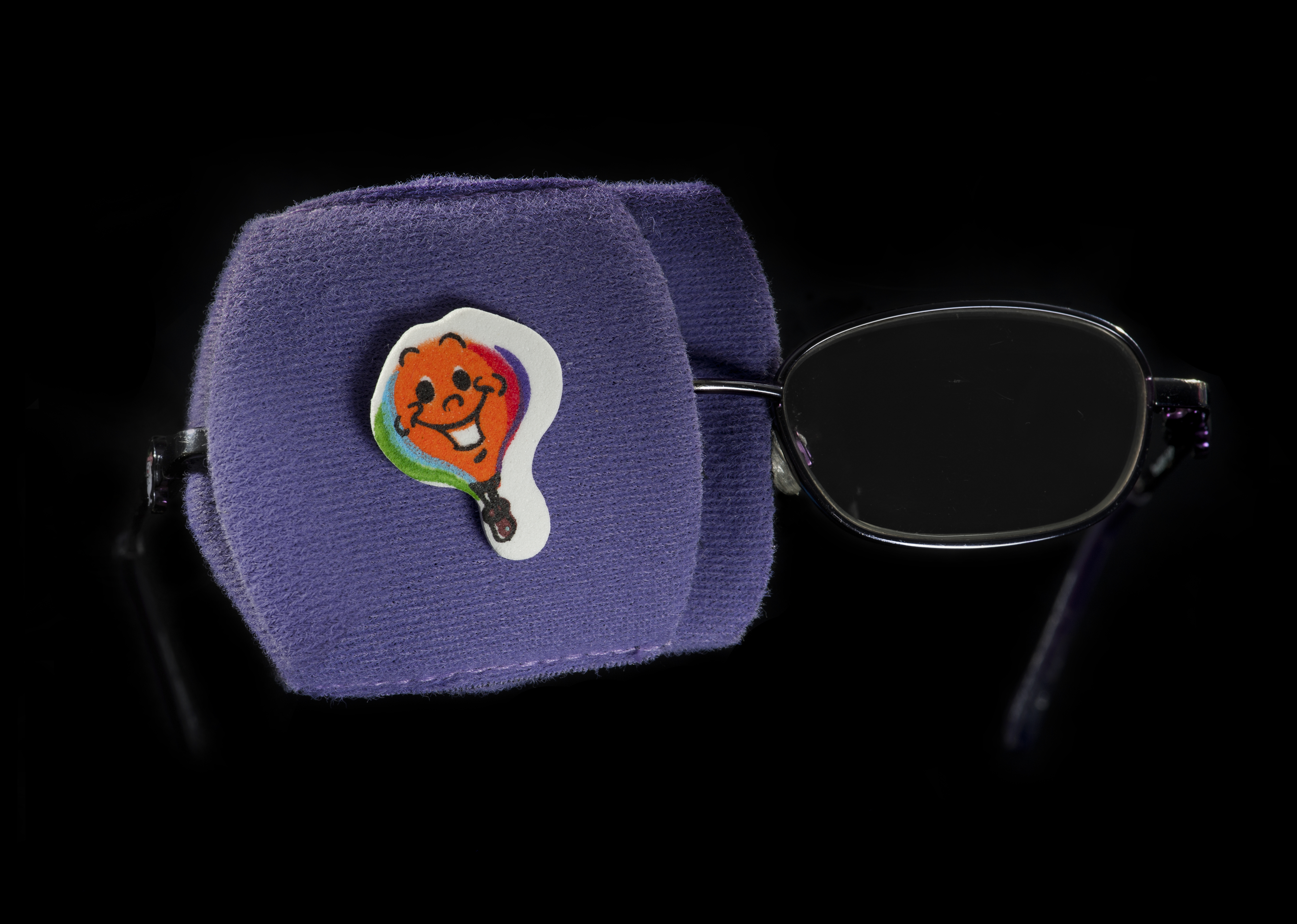 A colourful fabric patch attached to one lens of a pair of glasses
