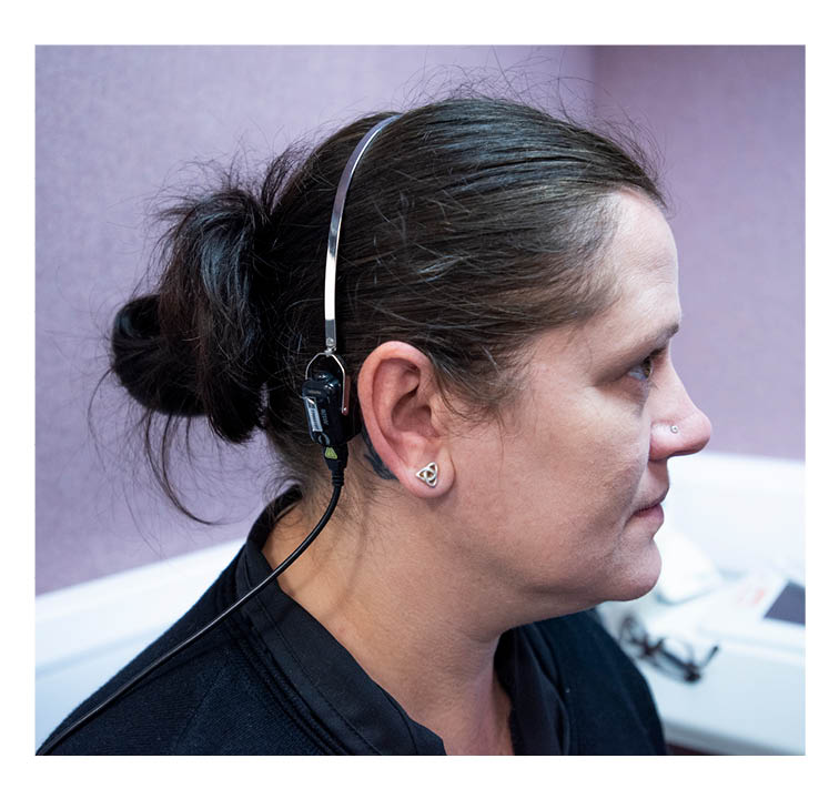 Patient wearing headband in soundproof audiology room.