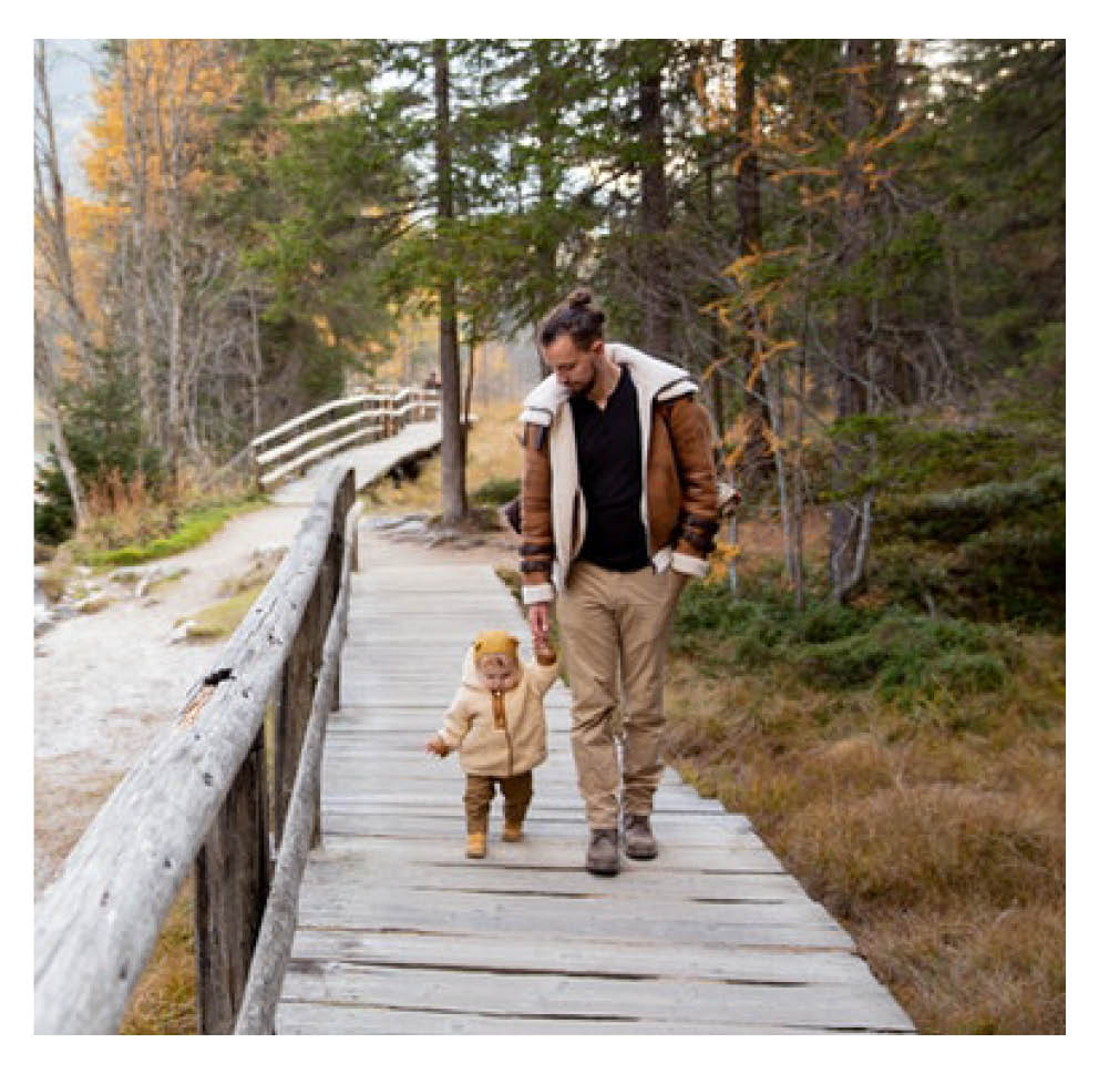 Parent walking up wooden ramp, holding their child's hand.